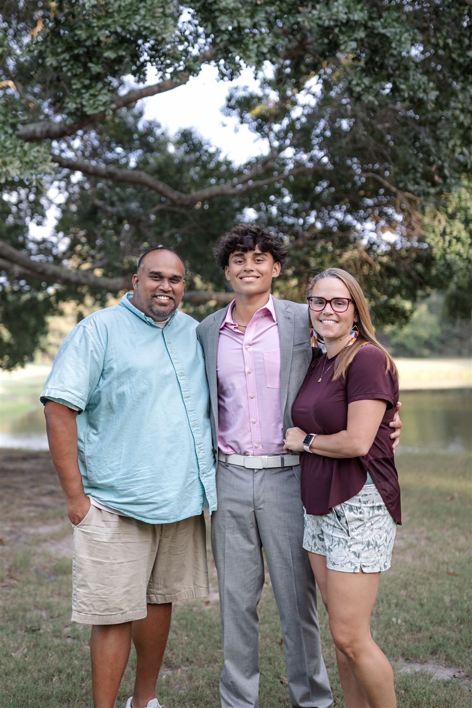 Jason Karamath with his wife and son outdoors under the trees